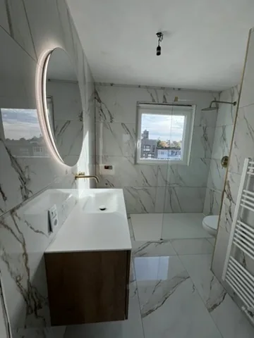 Afgewerkte badkamer met marmerlook en ronde spiegel